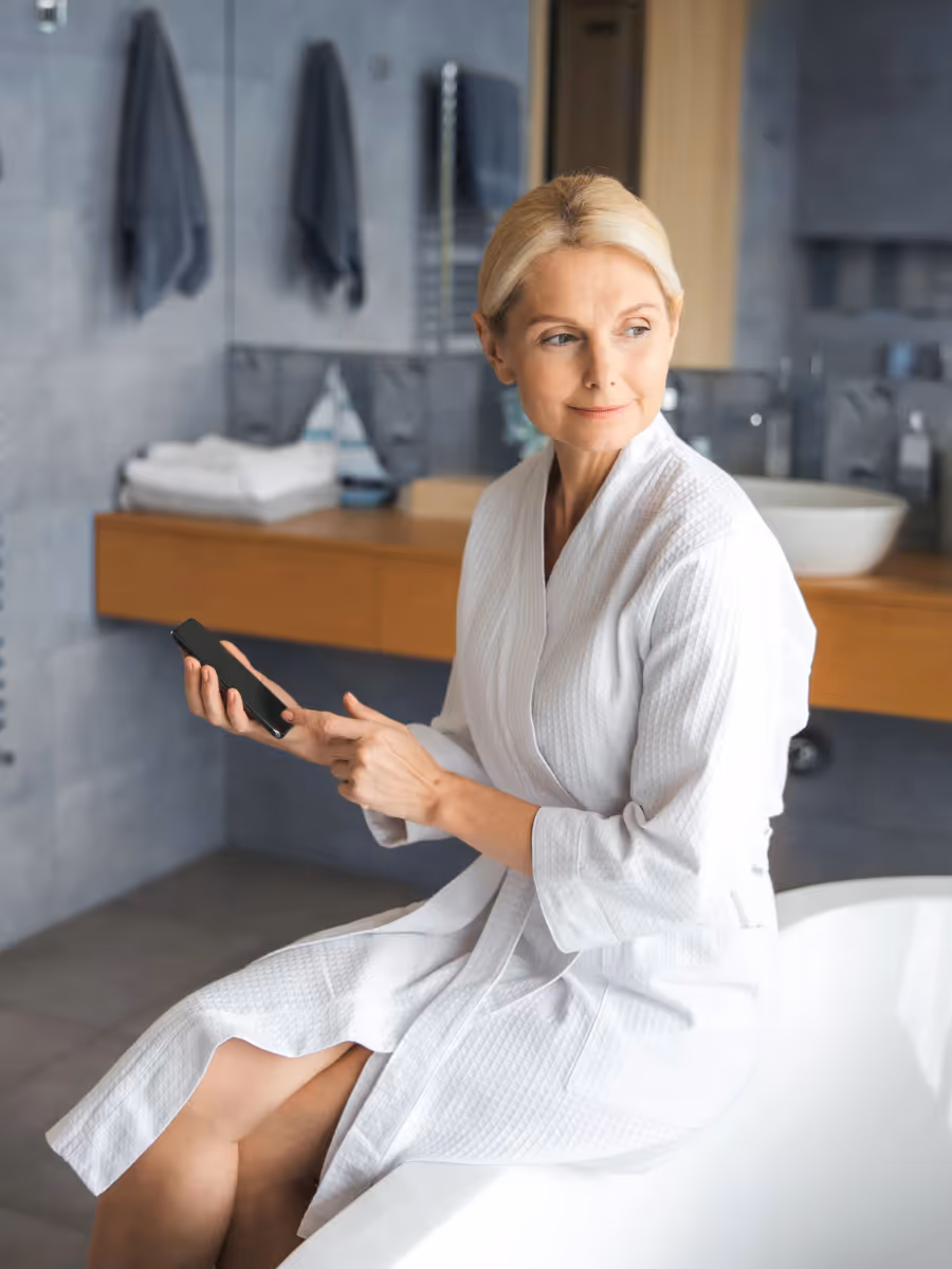 Frau im modernen Bad genießt einen entspannten Start in den Tag – Badmodernisierung für mehr Komfort und Leichtigkeit.