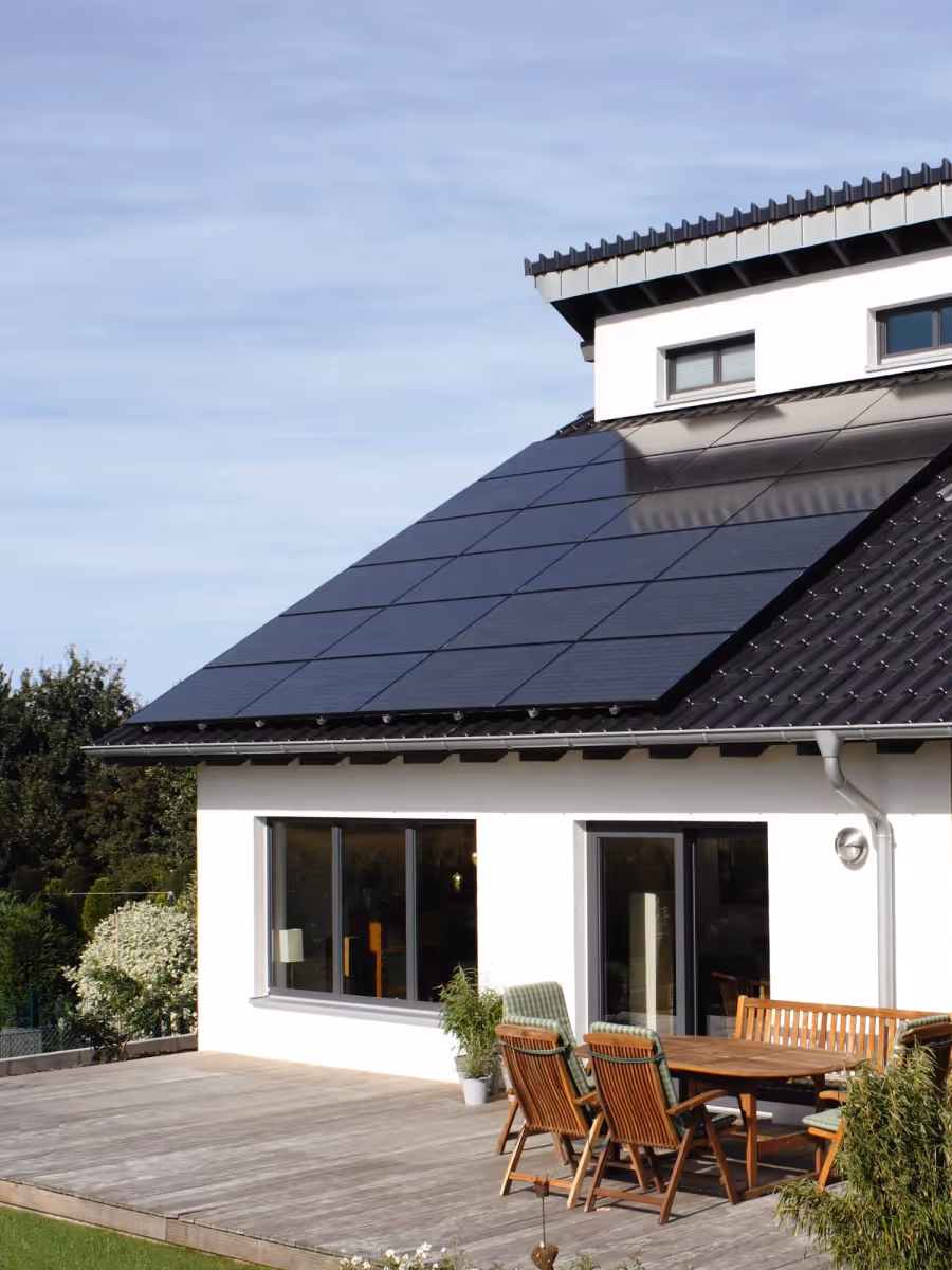 Wohnhaus mit Solaranlage auf dem Dach und Terrasse im Garten.