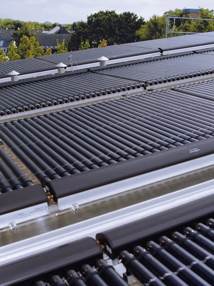 Große Solarthermieanlage mit Röhrenkollektoren auf einem Gebäudedach.