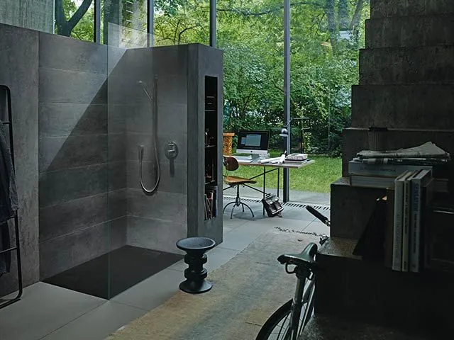 Offene Dusche mit dunklen Steinfliesen und bodengleichem Einstieg.