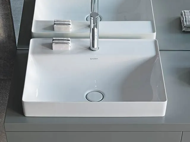 Zwei moderne weiße Waschtische mit einer hohen verchromten Armatur.