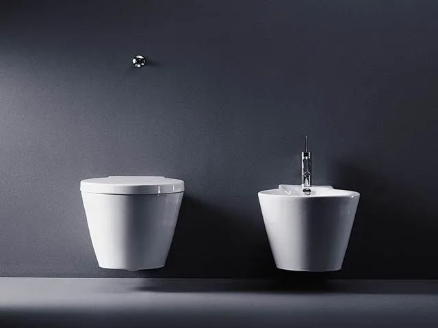 Wandhängendes WC und Bidet aus weißer Keramik vor einer anthrazitfarbenen Wand.