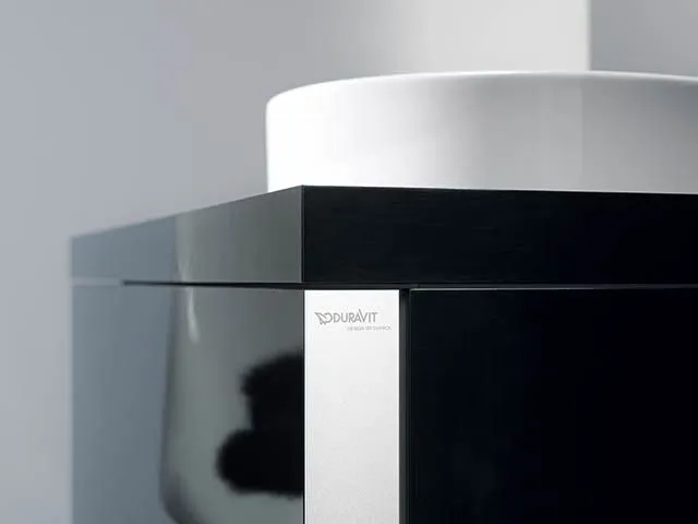 Schwarzer Waschtischunterschrank mit weißem Aufsatzwaschbecken.