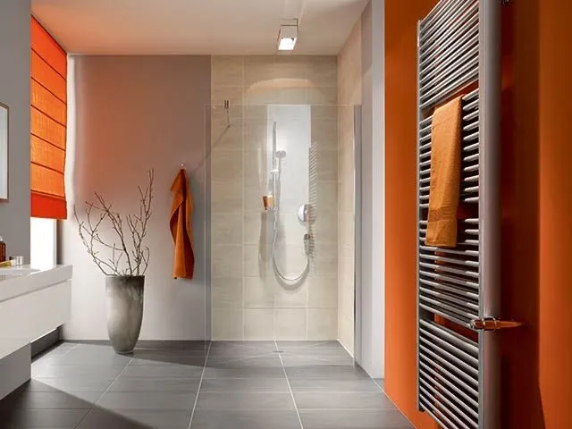 Modernes Bad mit bodengleicher Dusche und orangefarbenem Handtuchheizkörper.