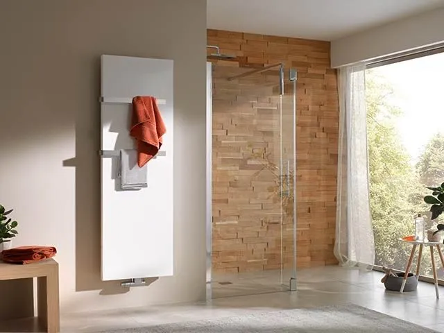 Weißer flacher Designheizkörper mit orangefarbenem Handtuch vor einer Echtholz-Duschwand im Bad.