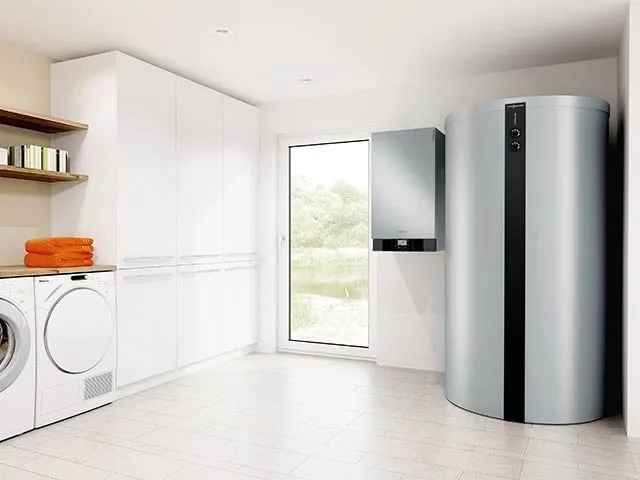 Wandhängendes Gas-Heizgerät mit silbernem Warmwasserspeicher in einem hellen Hauswirtschaftsraum.