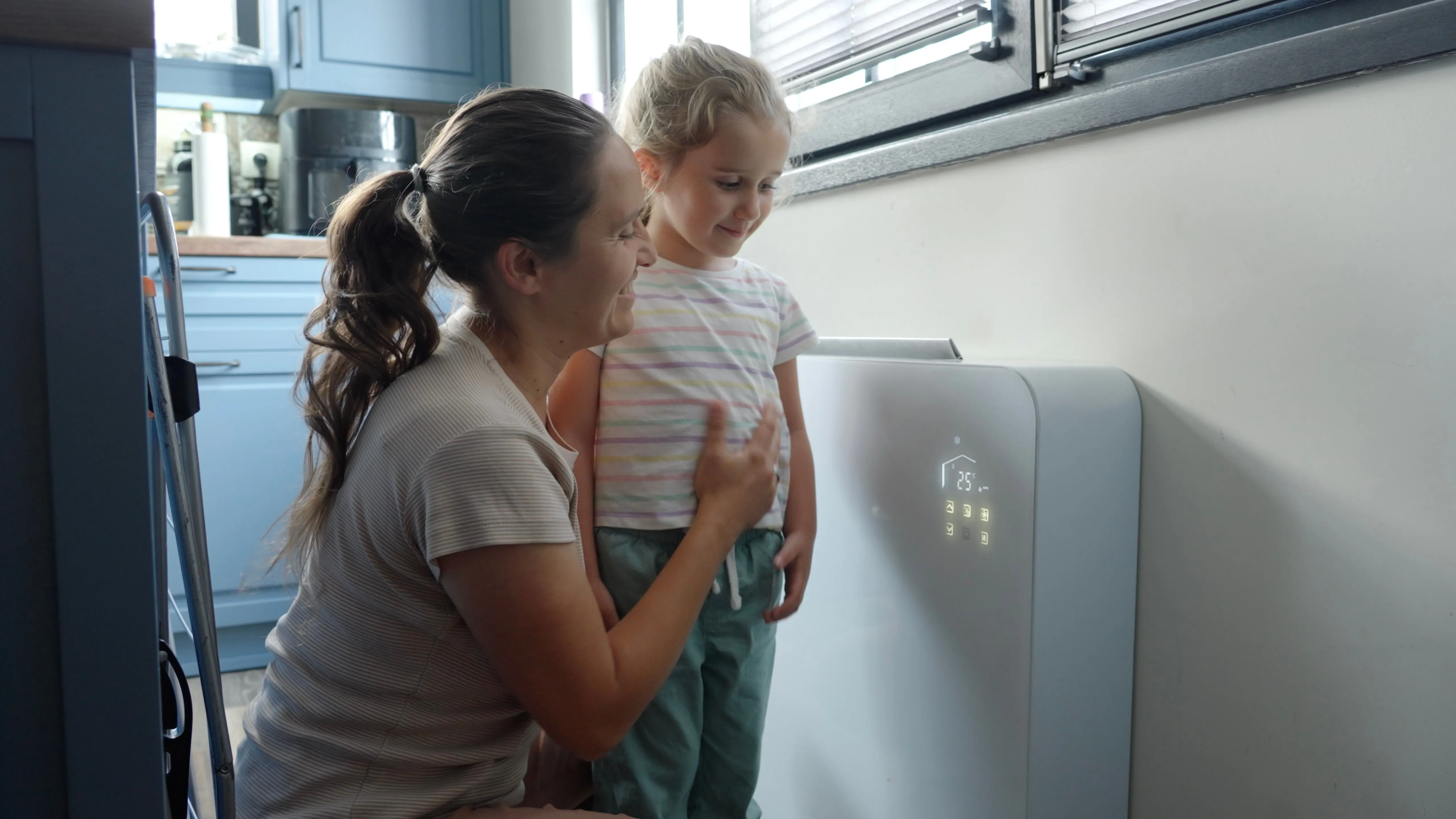 Mutter und Tochter stellen gemeinsam die Raumtemperatur an einem modernen Heizgerät mit Display ein.