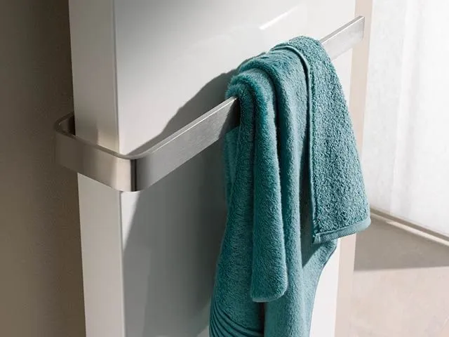 Schlanker weißer Designheizkörper mit Edelstahl-Handtuchstange und türkisfarbenem Handtuch.