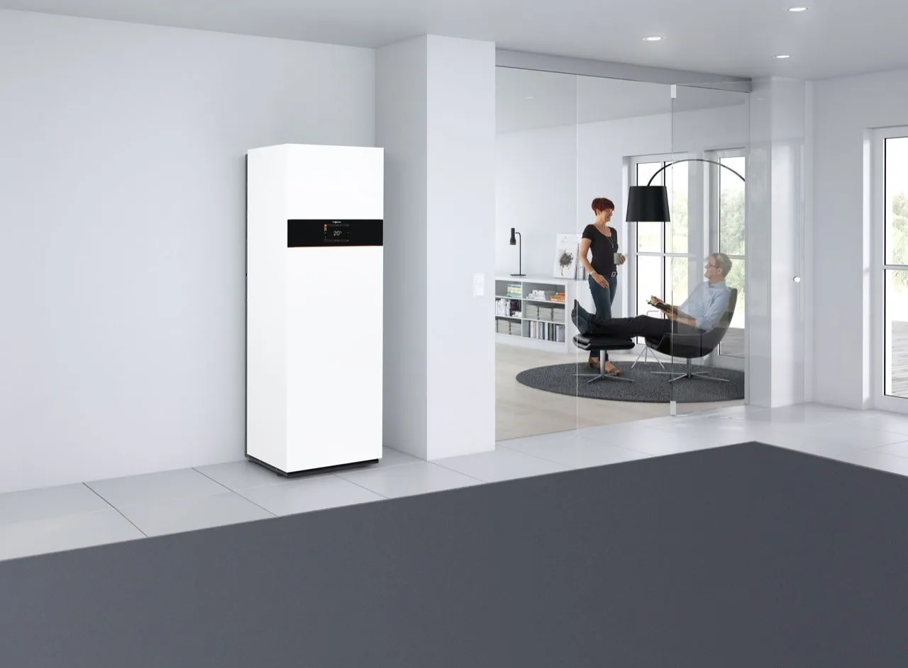 Bodenstehendes Gas-Brennwertgerät mit integriertem Speicher in einem hellen Wohnraum, im Nebenzimmer entspannt sich ein Paar.