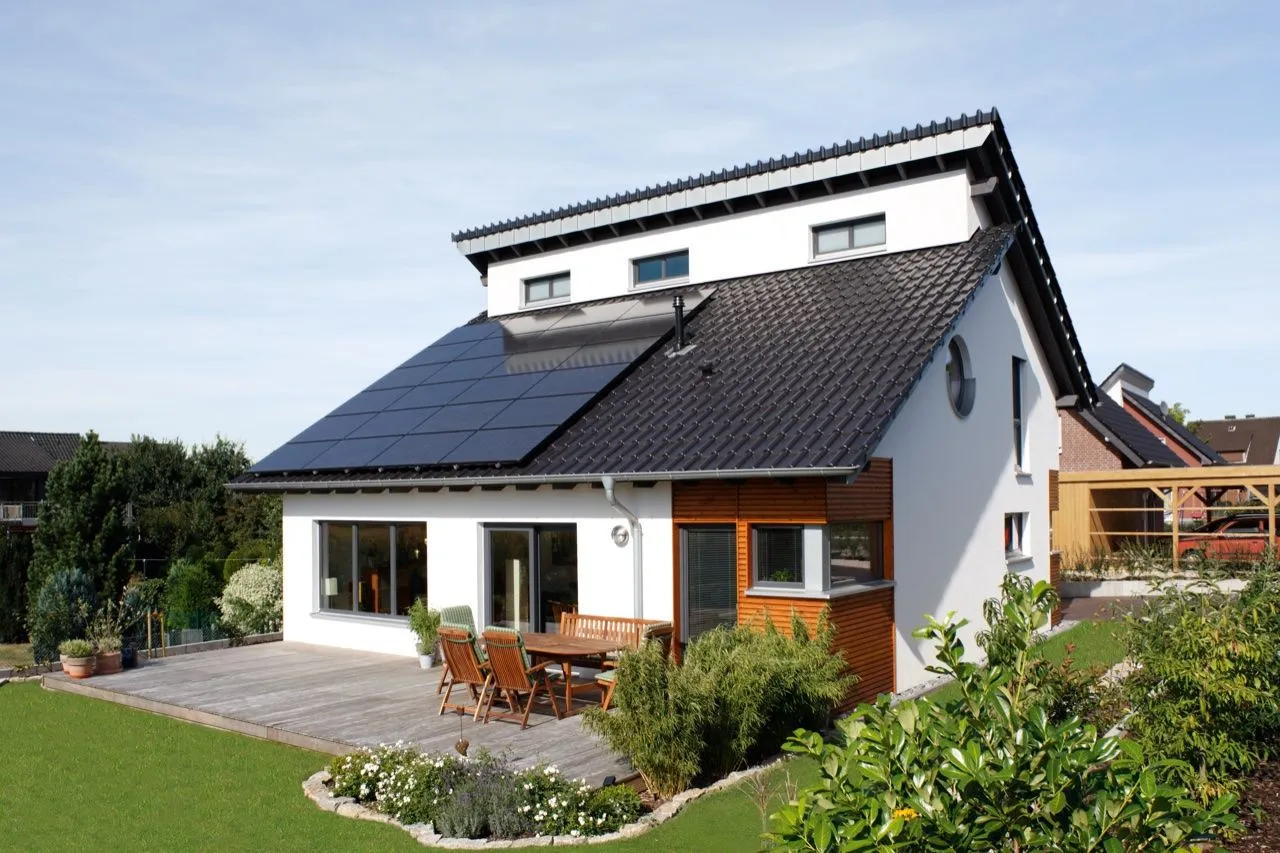 Einfamilienhaus mit Photovoltaikanlage auf dem Dach und sonniger Gartenterrasse.