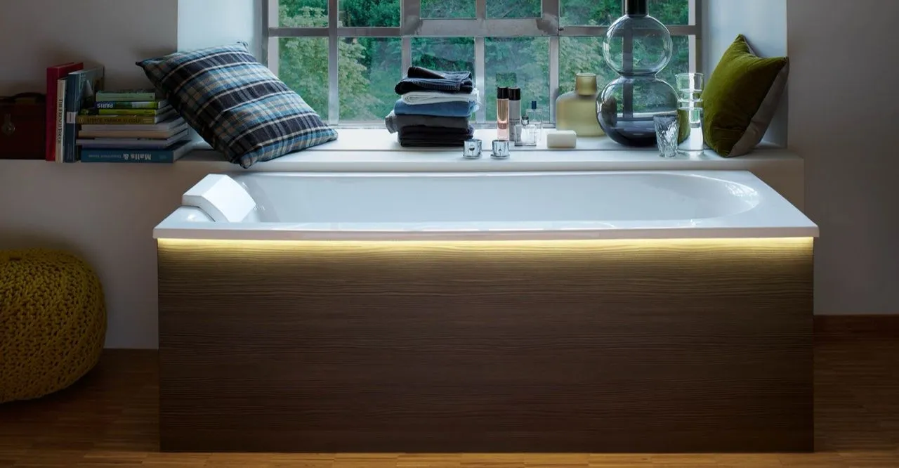 Beleuchtete Badewanne mit Holzverkleidung in einer gemütlichen Fensternische.