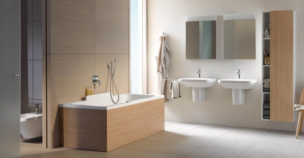 Modernes Bad mit holzverkleideter Badewanne, Bidet und zwei wandhängenden Waschtischen.