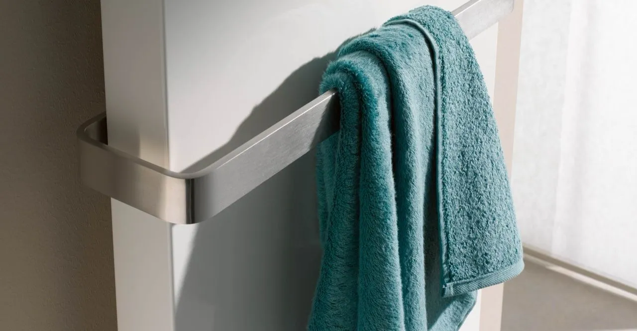 Weißer Designheizkörper mit Handtuchbügel und türkisfarbenem Handtuch.