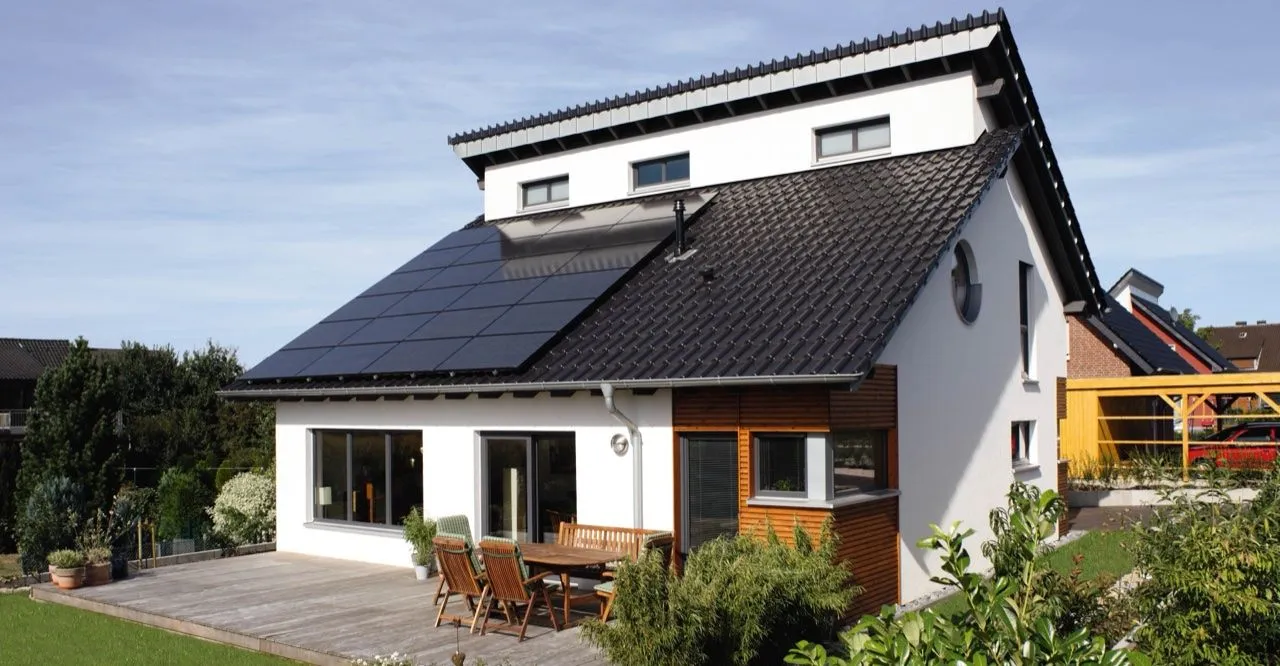 Photovoltaikanlage auf dem geneigten Dach eines Einfamilienhauses mit Gartenterrasse.